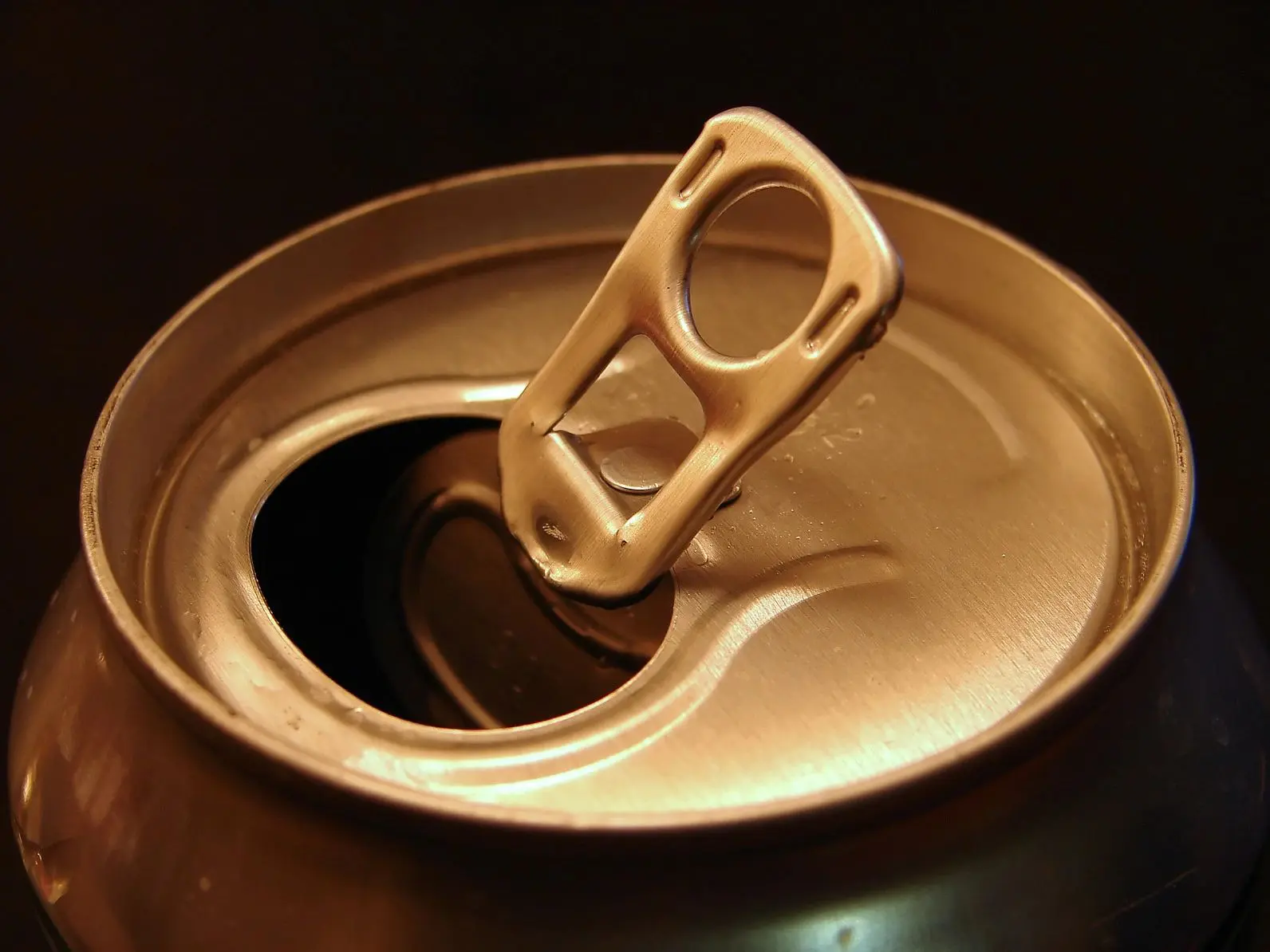 Close-up of an opened soda can with a metallic pull tab.